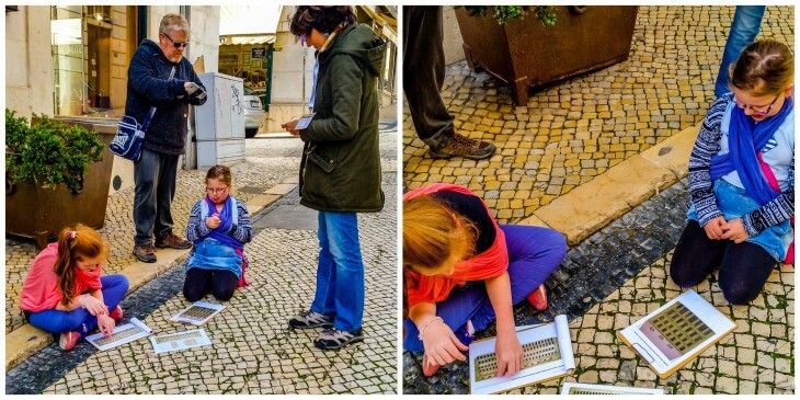 The girls are completing their work sheets on the pavement as Mark and Mariana from Little Lisbon Tours for kids watch on.