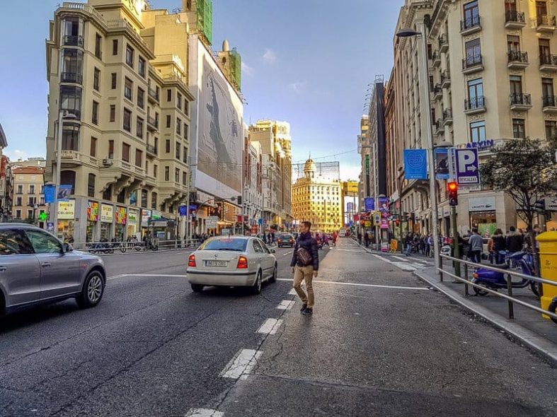 teenagers is about to cross the iconic Gran Vía street in Madrid
