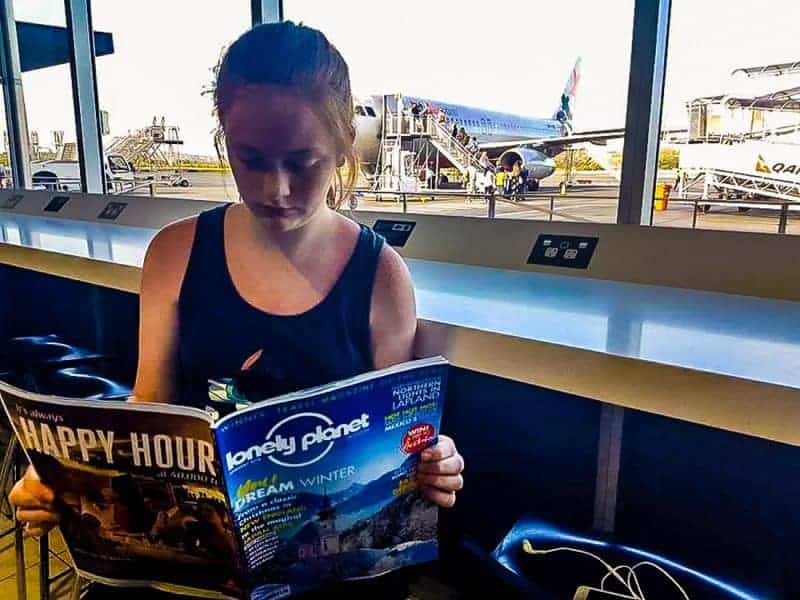 A girl reading a book with plane in back ground at Gold Coast Airport