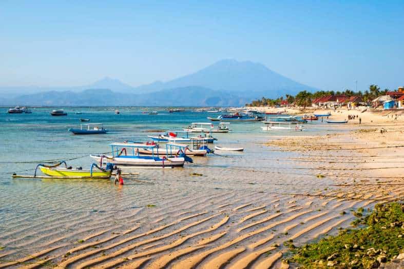 the beach on Nusa lembongan in Bali with boar and Nusa Penida in the back ground