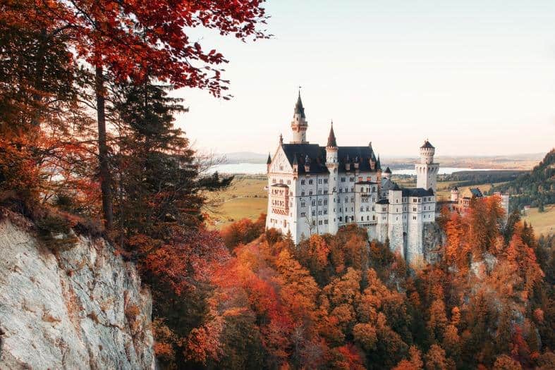 Neuschwanstein Castle, surrounded by autumn coloured leaves. The orange and brown of the trees makes the white castle with its blue roof really stand out against the backdrop.
Munich to Neuschwanstein Castle