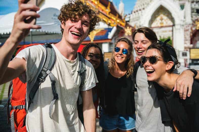 a group of teenagers taking a selfie in fromt of a temple in Bangkok