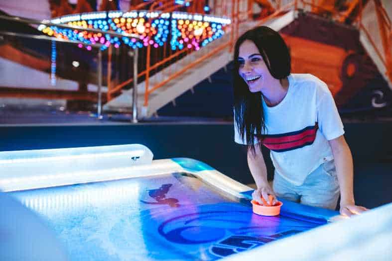 a teen is having fun in amusement park. Playing table hockey.