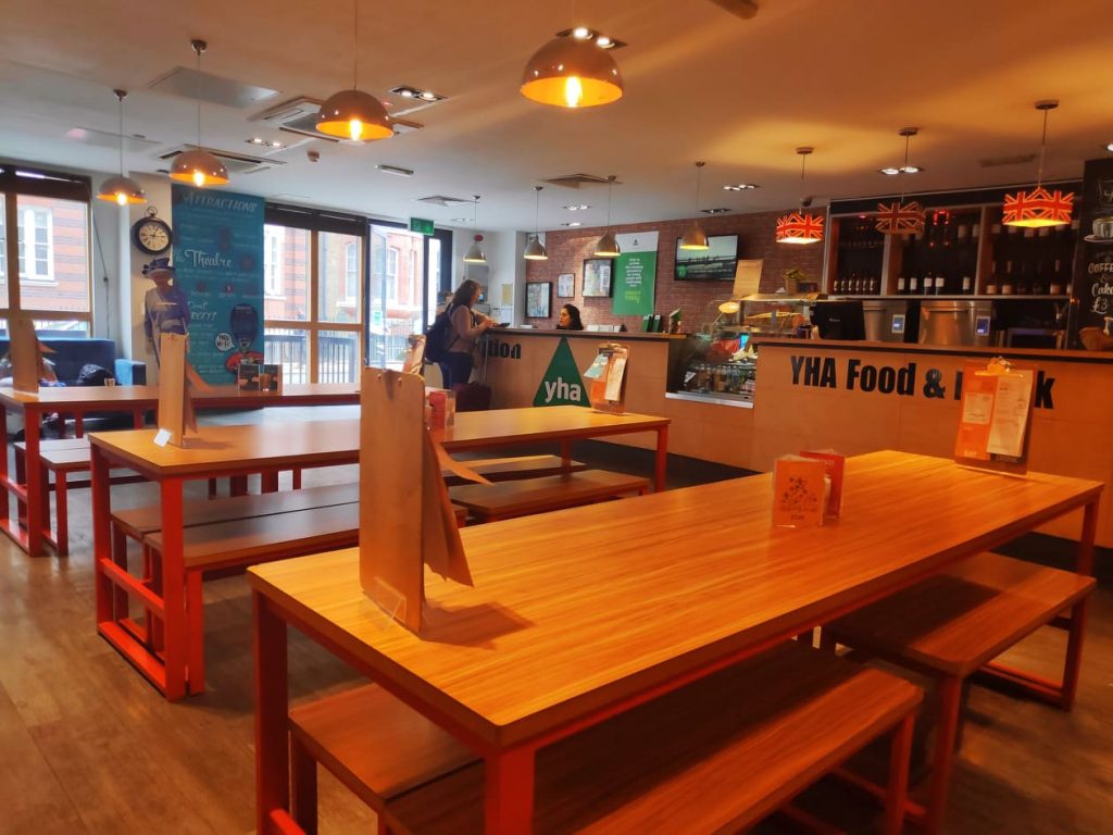 The check in desk at the YHA London Central has a large wooden desk in a light and airy room