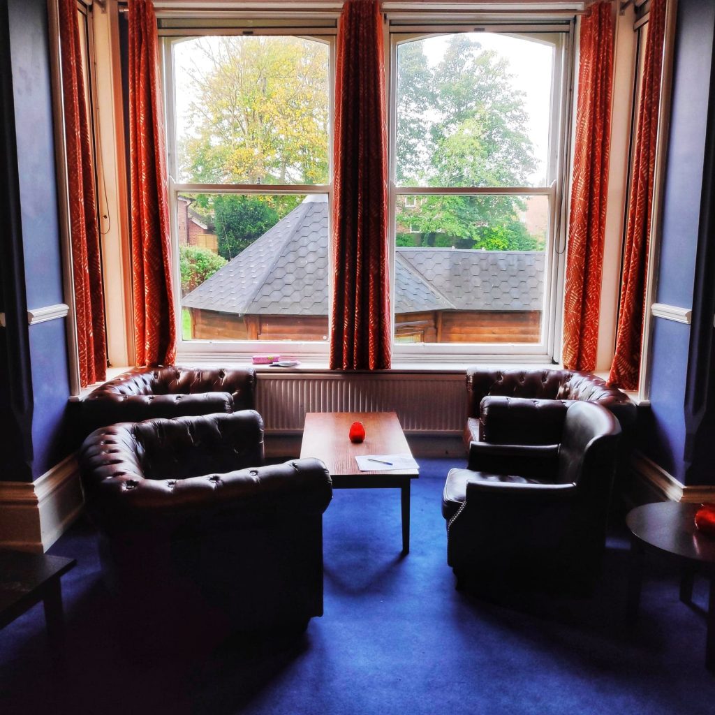 Communal lounge at YHA Canterbury looking out into the very green back yard and the small hut that you can stay in