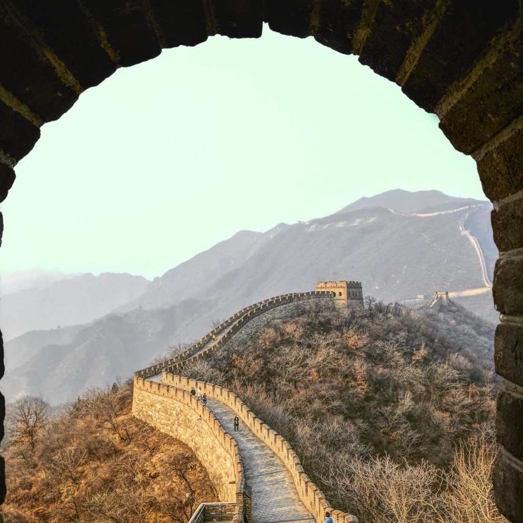 Scenic view of the Mutianyu section of the Great Wall of China, set against a backdrop of lush greenery and rolling hills