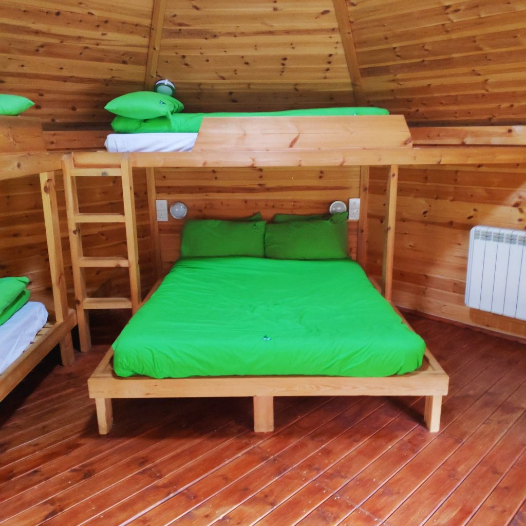 Cabin room at YHA Canterbury with a wooden interior, a double bed on the bottom bunk and a single on top