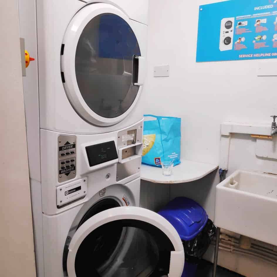 Laundry room at the Canterbury hostel with the dryer and washer stacked on top of each other