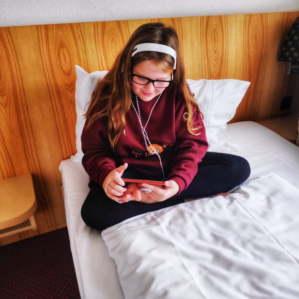 Teenage daughter sitting on her hotel bed in Zurich
