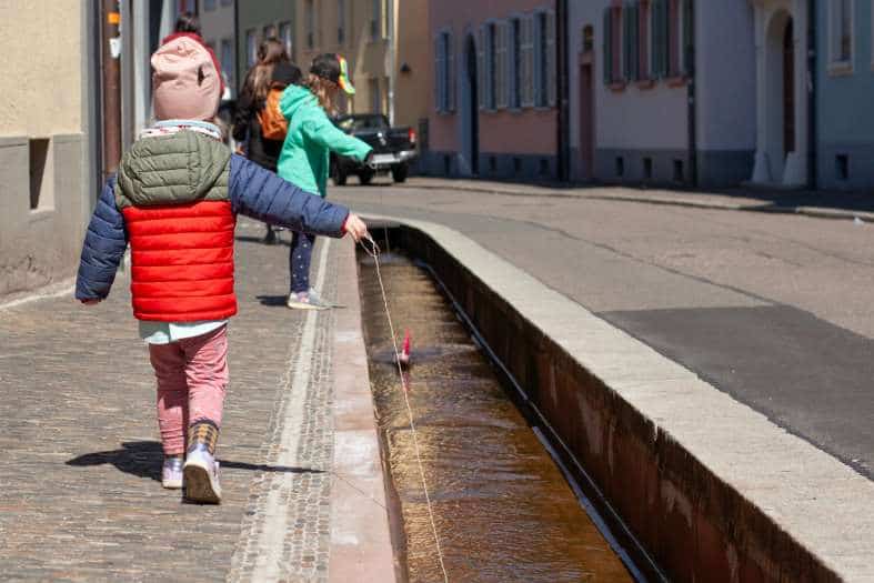 kids playing in the water flowing through the Bachle in Freiburg