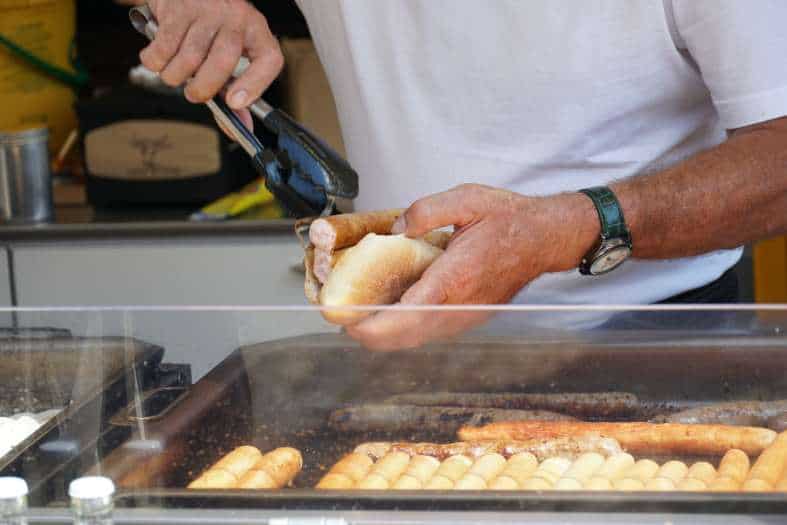 a sausage being put in a roll at a food stand in freiburg Germany