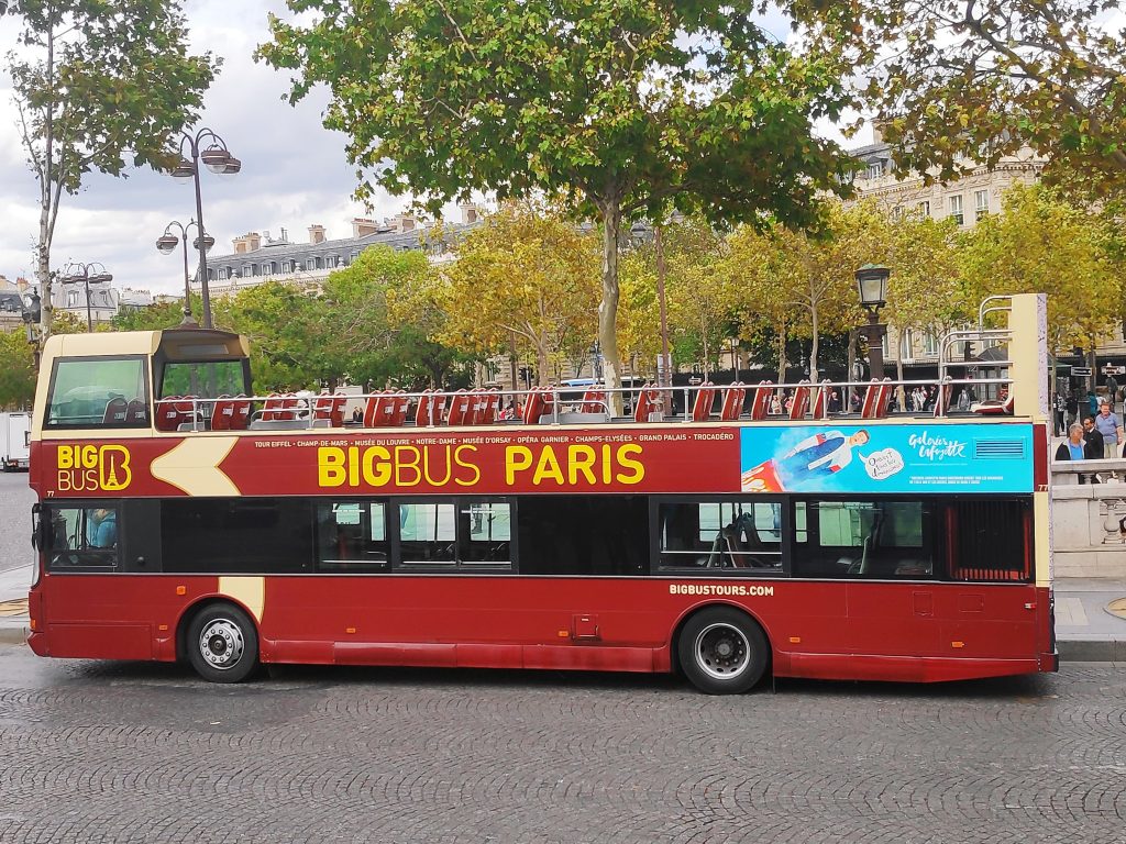 A red tour bus waiting for people to board before starting
