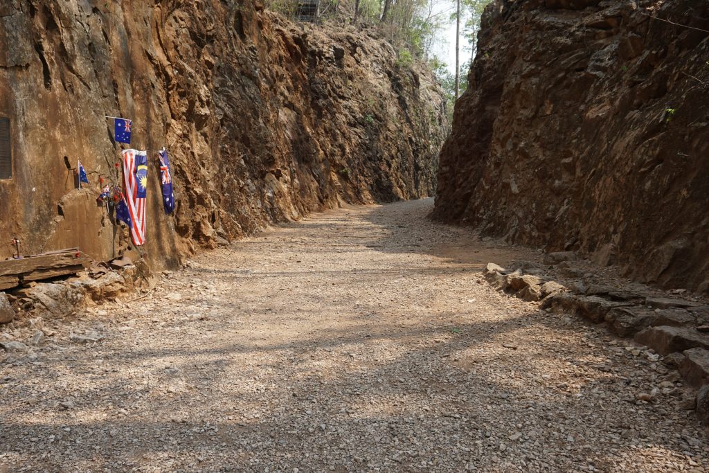 The cutting through solid rock where the old train line was laid. There are some flags on the side of the rocks from Nations that had POW's who worked on the train line