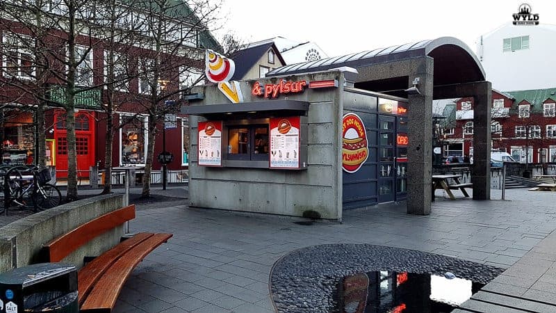 The small street side shop that sells the popular Icelandic hot dogs. It has plenty of tables and chairs around it in a town square