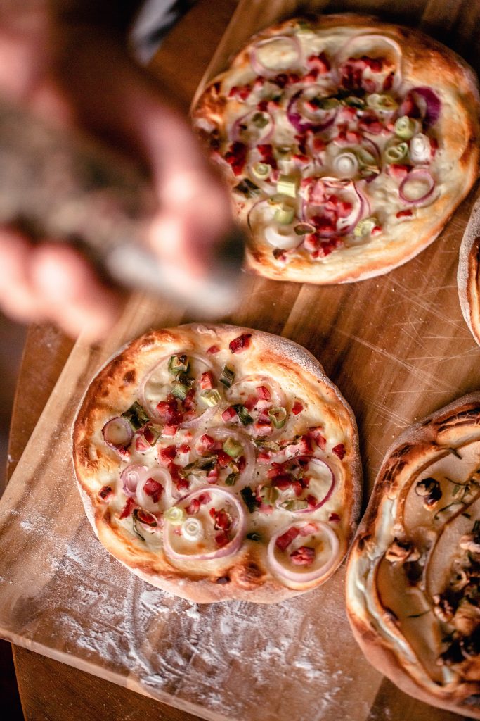 Some one is preparing the pizza like flammkuchen. It is a small round baked dough with onion, bacon and cheese on top but there seem to be other varieties in the peripheral of the picture too