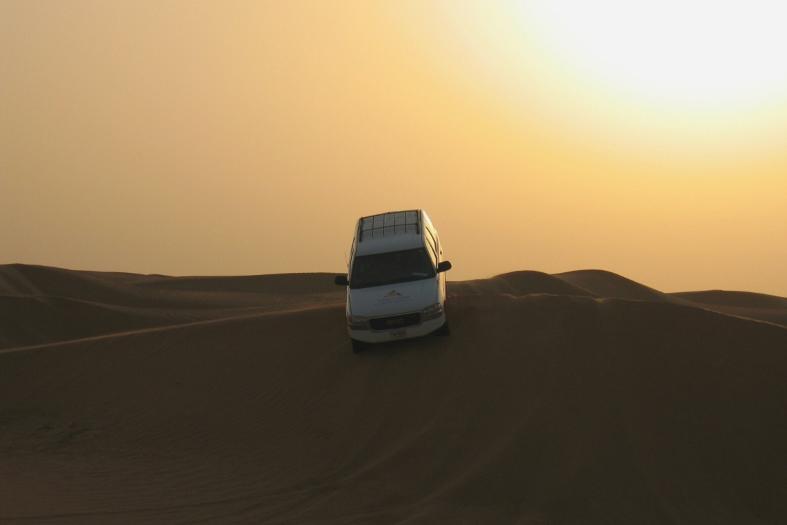 Cra driving over sand dunes in desert near Dubai