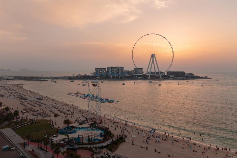 evening beach scene with ferris wheel and swimmers in Dubau