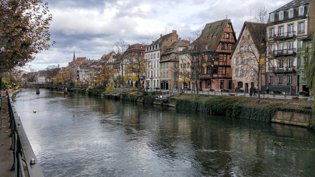 Fairytale houses line the canal in Strasborg. The water is rushing and the sky is a dull gray. The houses are all colours and the trees are bare of leaves or they have the last of the fall colours. Wandering the streets are some of the best things to do in the Alsace