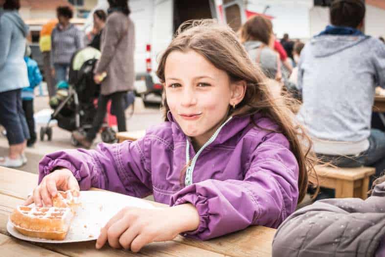 a young girl enjoying a belgium waffle in bruges