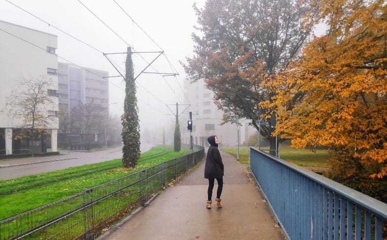 A teenager walking down a misty street in Freiburg Germany.