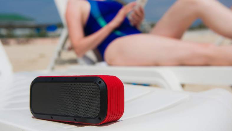 a teenager at the beach listening to her bluetooth speaker