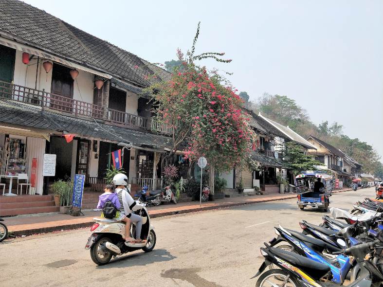 bustling street market in Luang Prabang filled with vibrant stalls offering colorful textiles, handcrafted goods, and local produce