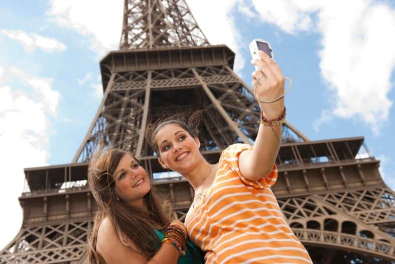 2 teenage girls in Paris France taking selfies in front of the Eiffel Tower