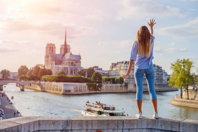 a teenage girl watching a boat go down the Seine River in Paris