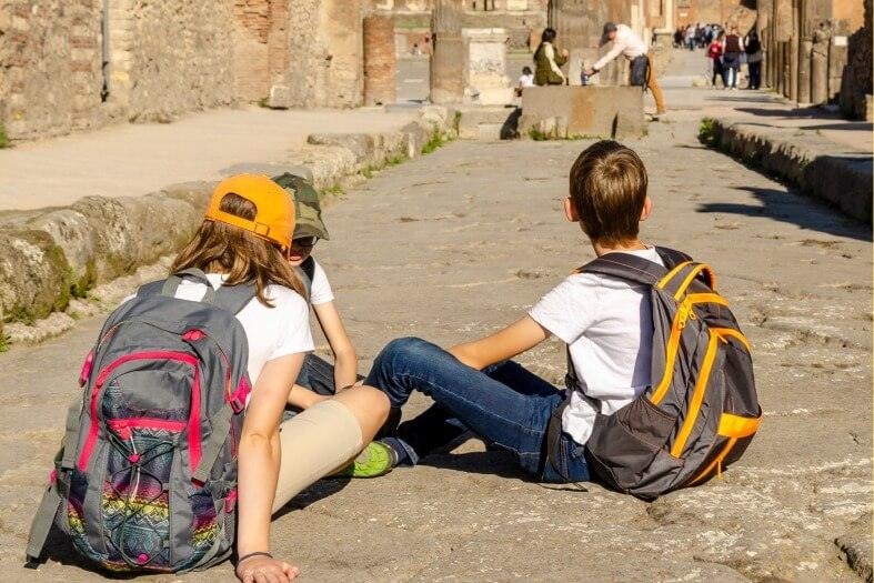 3 teenage boys sitting on the ancient streets of Pompeii
