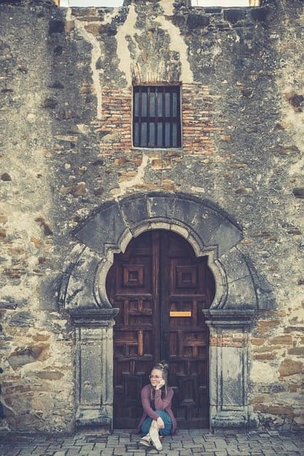 a teenage girl sitting out front of the Mission espada
