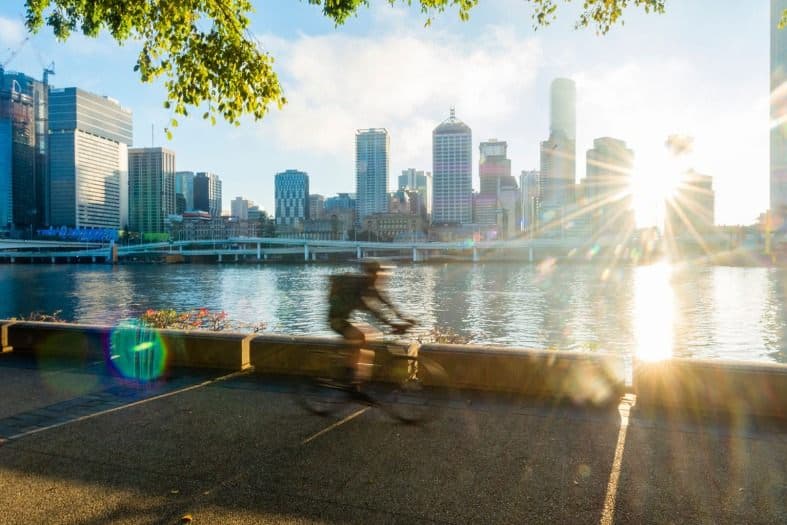 teenager pedaling along a scenic riverside pathway in Brisbane, Queensland