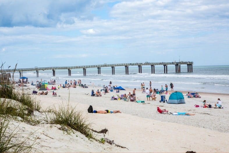 People lying on thh beack in St Augustine with the pier in the back ground