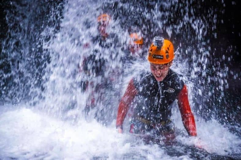 Adventurers descending a cascading waterfall, surrounded by lush greenery in the Azores