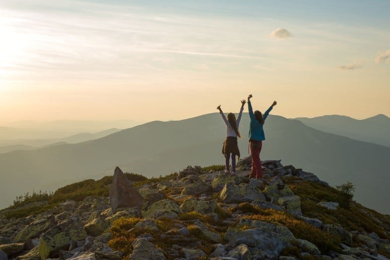 Two teen girls on a hike while camping in the woods.