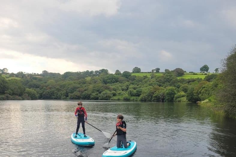 2 teens trying out stand up paddleboarding in Wales