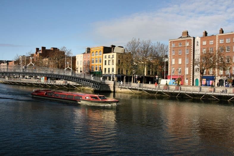 vibrant scene with a colorful tour boat gliding along the river, carrying enthusiastic passengers on a scenic boat tour on the River Liffey in Dublin, Ireland