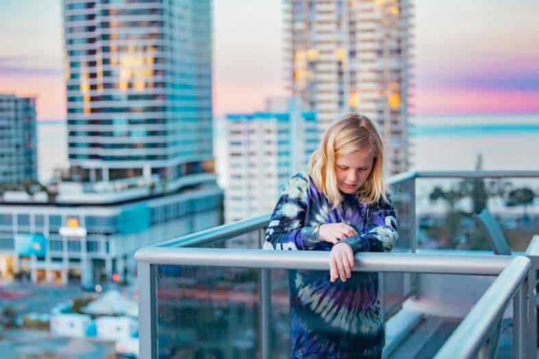 a young teenage boy standing on a balcony of a high rise