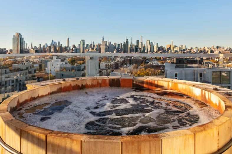 an apartment with a hot tub overlooking New York city