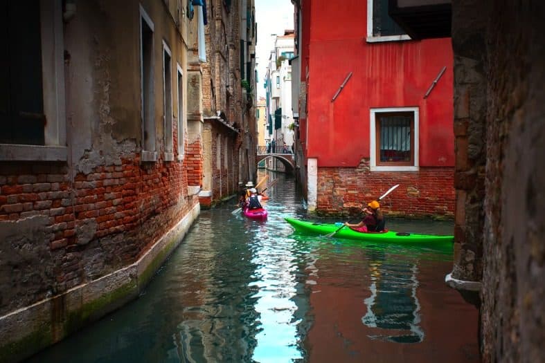A serene view of parents and kids kayaking along the canals in Venice