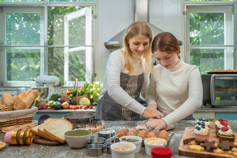 A cooking instructor teaching a teen in Prague how to cook