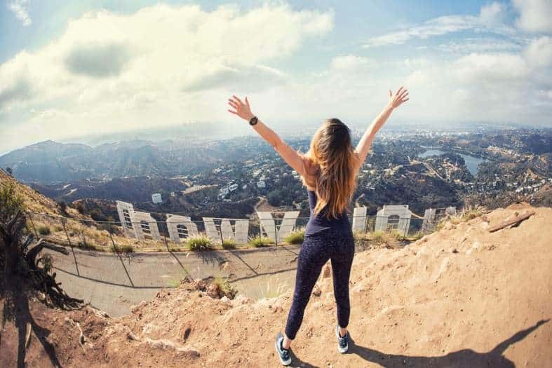 a teenager in Los Angeles standing behind the famous Hollywood sign