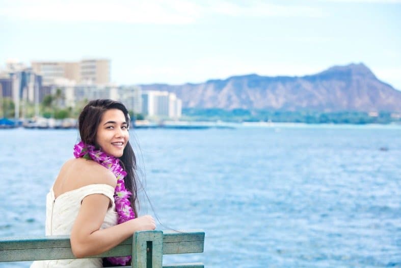 a teenage girl sitting by the water in hawaii