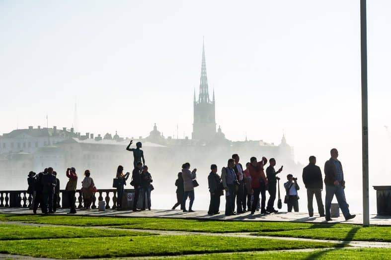 People having fun in a park with Stockholm town hall in the background