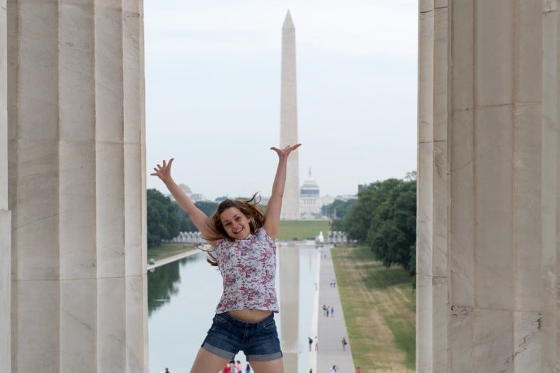 a teenage girl in Washington jumping with the Washington monument in the background