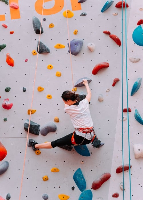 a teenage girl climbing a verticle indoor wall