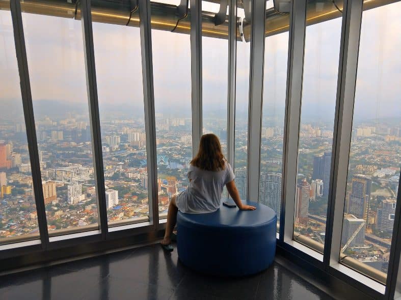 A teenage girl look out the windows at the Petronas towers