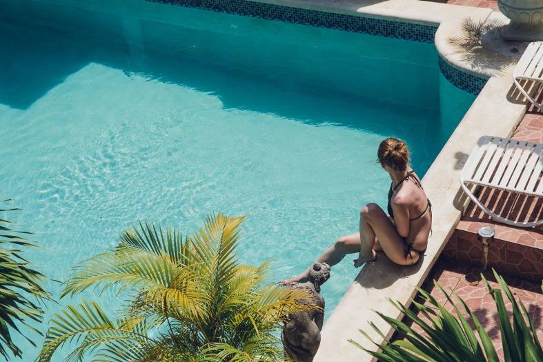 A teenage girl sitting at a pool in the sun in Miami
