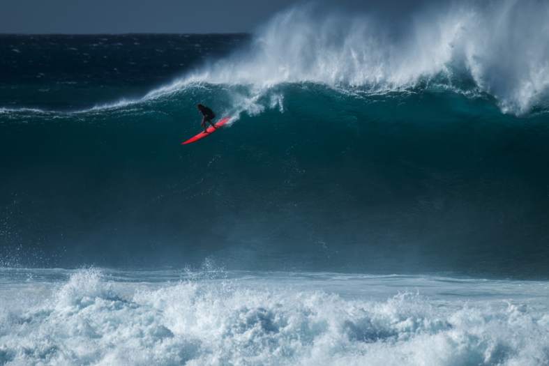 a surfer on the face of a big wave at pipeline on the north shore of Hawaii