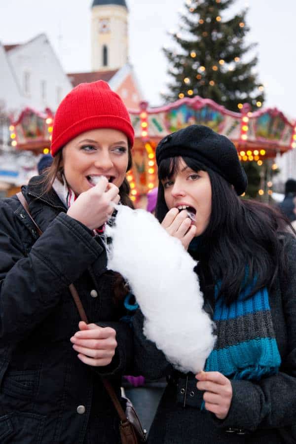A mum and daughter having fun and eating food a christmas market