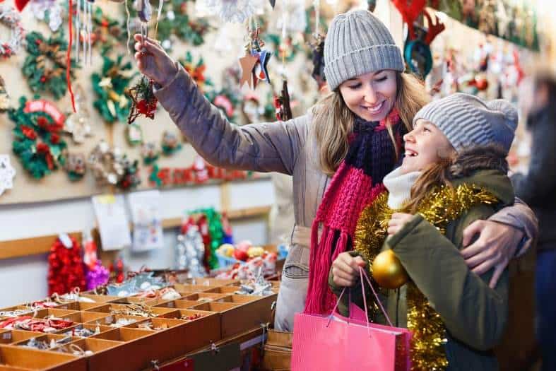 a mom and a young teen daughter having fun at a christmas market laughing